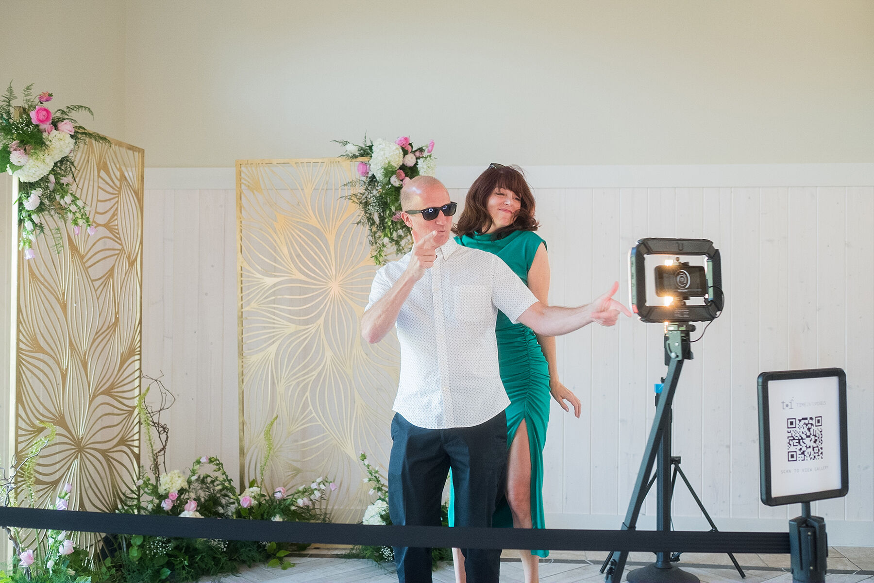 Couple on a 360 photo booth at a Minnesota wedding with a gold and floral backdrop