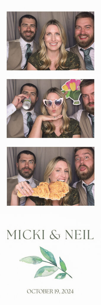 three people posing in a photo booth with props